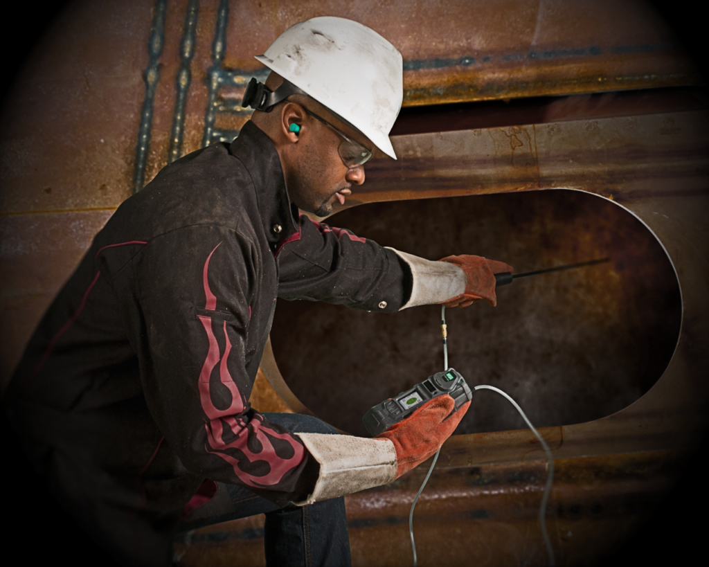 Trabalhador utilizando um detector de gases em conjunto com seu equipamento de segurança